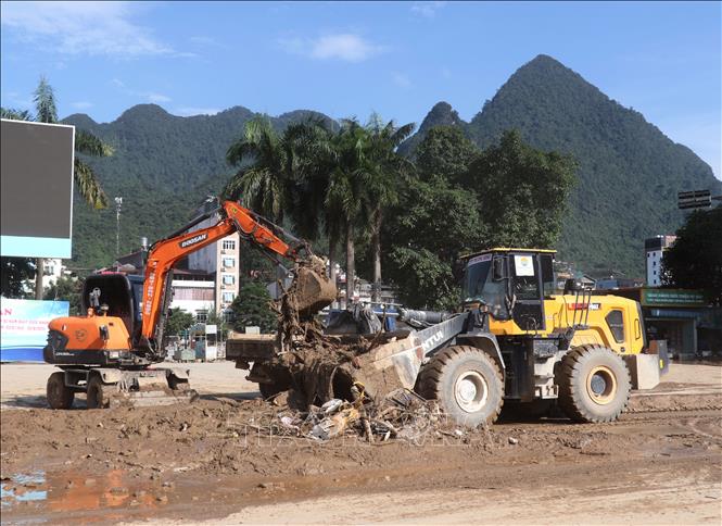 Rác thải dày đặc sau lũ, phải dùng tới các phương tiện cơ giới để dọn dẹp. Ảnh: Đức Thọ - TTXVN
