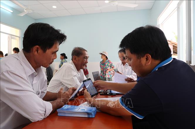 Nhân viên Xí nghiệp cấp nước Cần Giờ hướng dẫn người dân ở Cù lao Mỹ Khánh cài đặt ứng dụng chăm sóc khách hàng và đóng tiền nước online qua ứng dụng thanh toán. Ảnh: Anh Tuấn – TTXVN