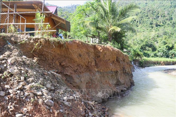 Lũ ống, lũ quét với dòng chảy xiết đã gây xói mòn, xâm thực vào gần nhà dân. Ảnh: Xuân Tiến - TTXVN 