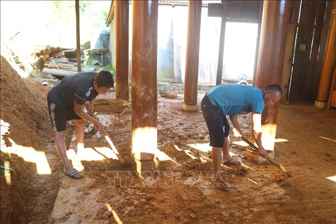 Người dân thu dọn bùn đất chảy tràn vào nhà do sạt lở vách ta-luy dương. Ảnh: Xuân Tiến - TTXVN