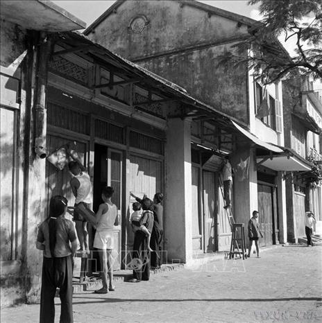 Từ sáng sớm, người dân Hà Nội treo cờ, khẩu hiệu trước cửa nhà, đón chào bộ đội về giải phóng Thủ đô. Ảnh: Tư liệu TTXVN