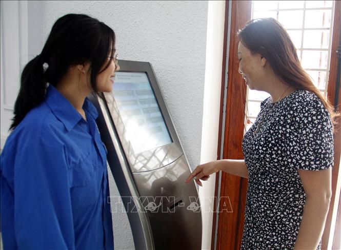 Đoàn viên hướng dẫn người dân bấm số thực hiện thủ tục hành chính tại Trung tâm phục vụ hành chính công. Ảnh: Đồng Thúy-TTXVN