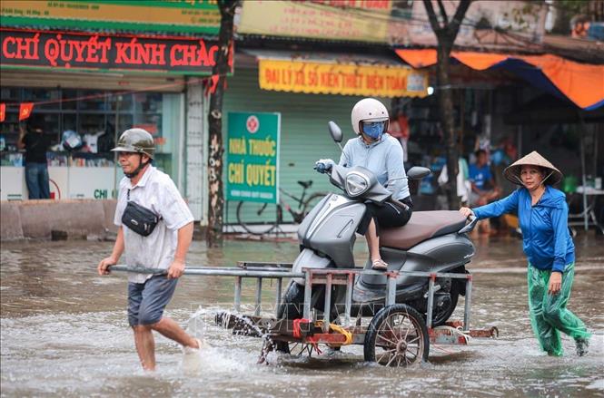 Người dân phải thuê xe chở qua vùng ngập nặng trên đường Cầu Bươu. Ảnh: Hoàng Hiếu - TTXVN