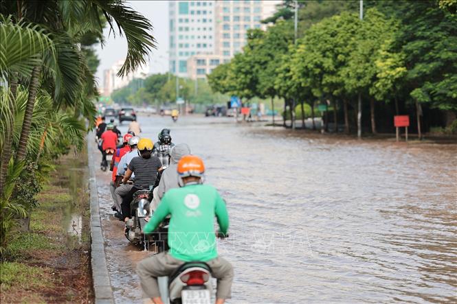 Nhiều phương tiện tham gia giao thông qua nút Dương Đình Nghệ - Phạm Hùng phải nép sát để tránh ngập. Ảnh: Lê Đông - TTXVN