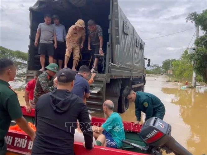 Do nhiều tuyến đường trong thôn An Lạc, xã Trung Giã (Hà Nội) đã ngập sâu, lực lượng chức năng dùng thuyền và ô tô chuyên dụng đưa người dân di tản an toàn. Ảnh: TTXVN phát