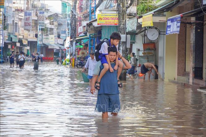 Một học sinh được người thân cõng đến trường do đường Bùi Hữu Nghĩa (phường Bình Thủy) bị ngập ngày 8/10. Ảnh: Thanh Liêm - TTXVN