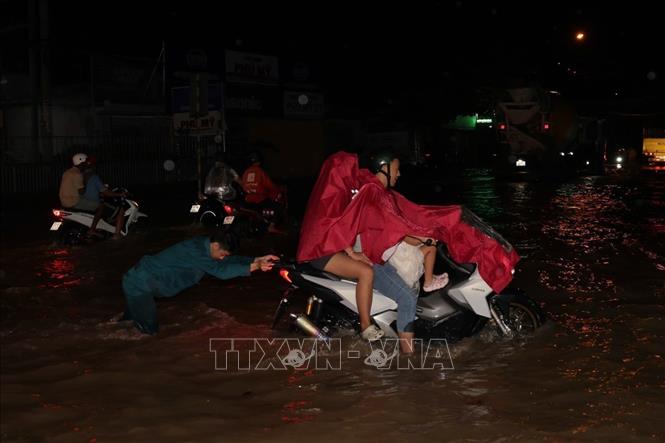 Lực lượng dân quân tự vệ giúp người đi xe máy vượt qua đoạn ngập sâu. Ảnh: TTXVN phát