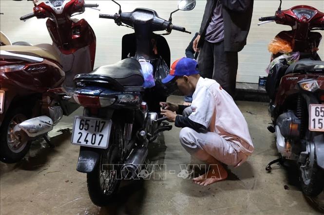 Nhân viên một cửa hàng xe máy hỗ trợ người dân sửa xe bị chết máy do đi qua các đoạn ngập sâu. Ảnh: TTXVN phát
