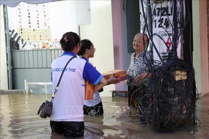 Sinh viên Đại học Cần Thơ tặng mì tôm cho bà Trần Ngọc Thụy (71 tuổi), có hoàn cảnh khó khăn ở khu vực chợ Bình Thủy có nhà bị ngập sâu khi triều cường lên. Ảnh: TTXVN phát