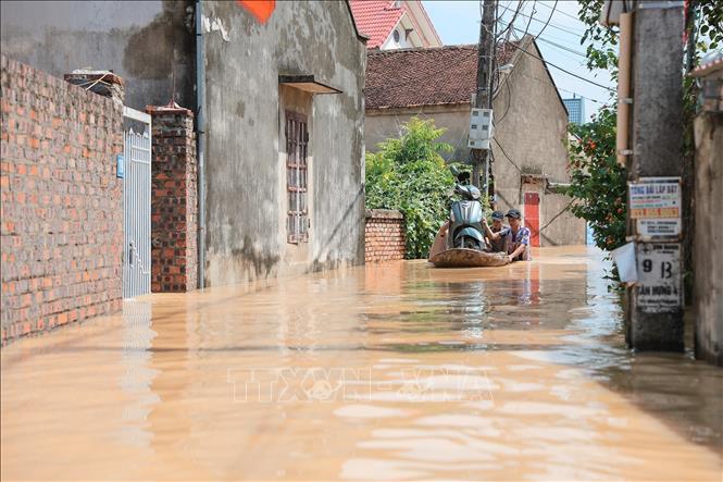 Người dân dùng thuyền di chuyển xe máy qua đoạn ngập sâu tại thôn Ngô Đạo, xã Đa Phúc, Hà Nội. Ảnh: Lê Đông - TTXVN