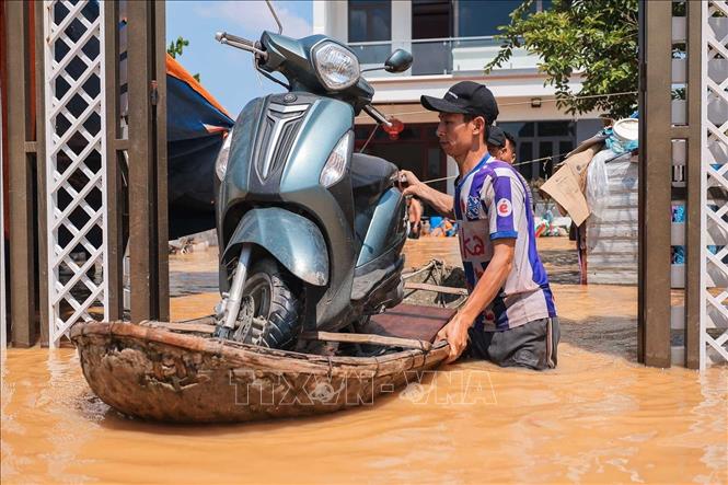 Người dân thôn Ngô Đạo, xã Đa Phúc (Hà Nội) di chuyển tài sản khỏi vùng bị ngập. Ảnh: Hoàng Hiếu - TTXVN