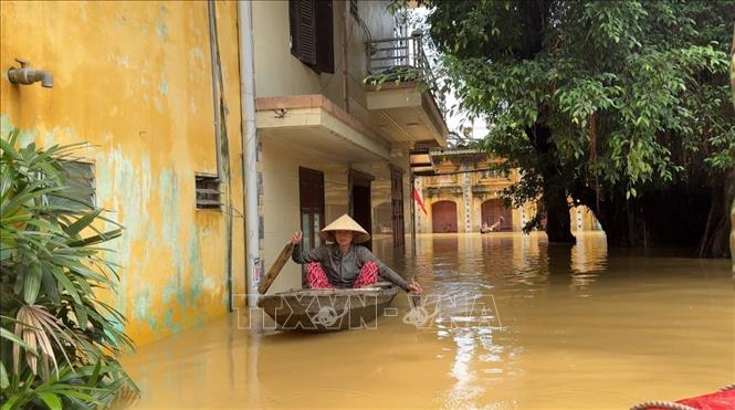 Người dân dùng thuyền di chuyển trong khu vực ngập sâu. Ảnh: Đỗ Huyền - TTXVN