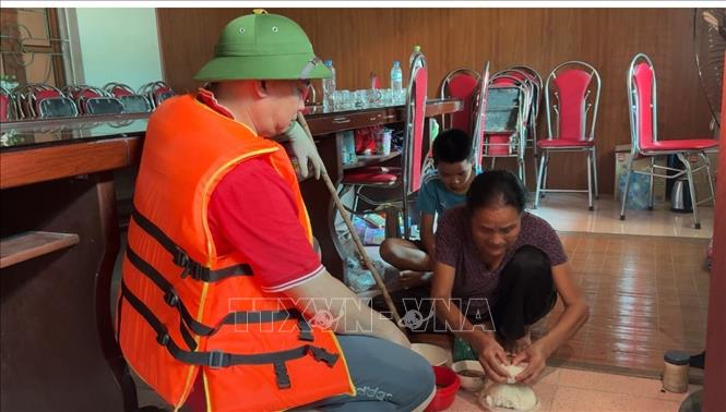Người dân vùng ngập sâu được hỗ trợ di chuyển đến nơi an toàn. Ảnh: Đỗ Huyền - TTXVN