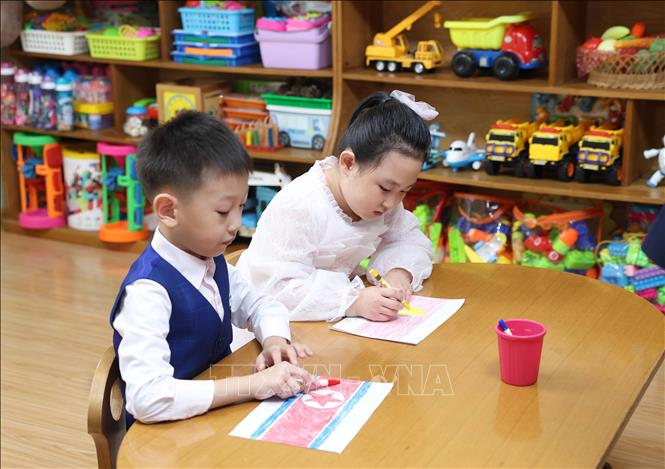 Thiếu nhi lớp học mang tên Chủ tịch Hồ Chí Minh vẽ và tô màu quốc kỳ Việt Nam và Triều Tiên. Ảnh: Thống Nhất – TTXVN