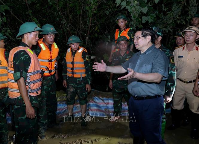 Thủ tướng Phạm Minh Chính động viên lực lượng đang đắp chống tràn, bảo đảm an toàn tuyến đê hữu Cầu. Ảnh: Dương Giang-TTXVN 
