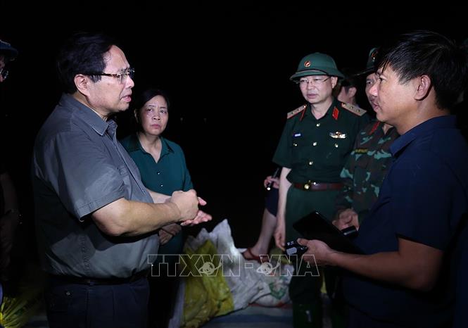 Thủ tướng Phạm Minh Chính động viên lực lượng đang đắp chống tràn, bảo đảm an toàn tuyến đê hữu Cầu. Ảnh: Dương Giang-TTXVN 
