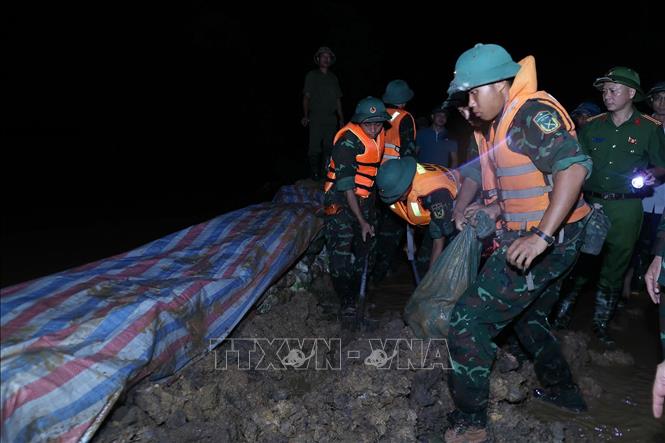 Các lực lượng đắp đê chống tràn, bảo đảm an toàn tuyến đê hữu Cầu. Ảnh: Dương Giang-TTXVN 
