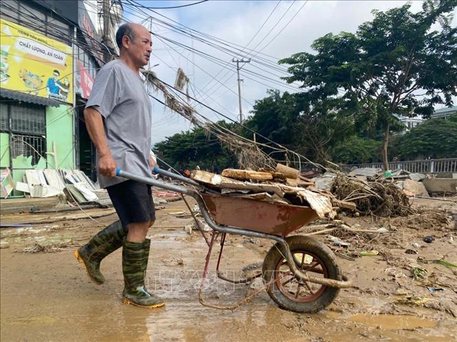 Một người đàn ông lớn tuổi ở phường Thục Phán vẫn lao động miệt mài để dọn đất bùn ra khỏi nhà. Ảnh: Quốc Đạt - TTXVN
