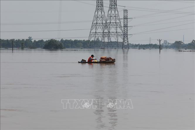 Mì gói, nước uống được lực lượng tình nguyện chuyển bằng thuyền nhỏ để đến các hộ dân. Ảnh: Phan Phương - TTXVN