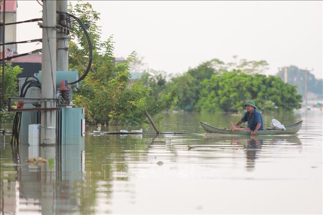 Người dân dùng thuyền để di chuyển trong nước lũ. Ảnh: Phan Phương - TTXVN