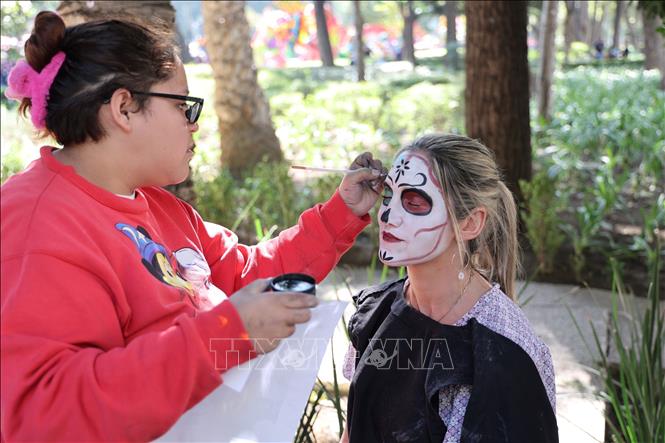 Nghệ nhân trang điểm cho du khách trong một lễ hội du lịch tại thủ đô Mexico City, Mexico.  Ảnh: Phi Hùng - PV TTXVN tại Mexico