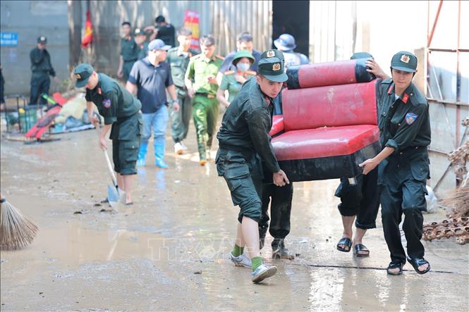 Các chiến sĩ Công an Hà Nội hỗ trợ người dân thu gom, vận chuyển tài sản hư hại do mưa lũ tại Đường Thành Công, xã Trung Giã, Hà Nội. Ảnh: Lê Đông - TTXVN