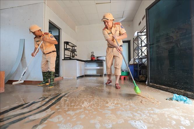Các chiến sĩ Công an Hà Nội hỗ trợ người dân dọn dẹp bùn đất thôn Nỷ, xã Trung Giã, Hà Nội. Ảnh: Lê Đông - TTXVN