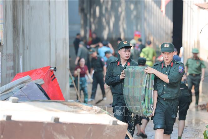 Các chiến sĩ Công an Hà Nội hỗ trợ người dân thu gom, vận chuyển tài sản hư hại do mưa lũ tại Đường Thành Công, xã Trung Giã, Hà Nội. Ảnh: Lê Đông - TTXVN