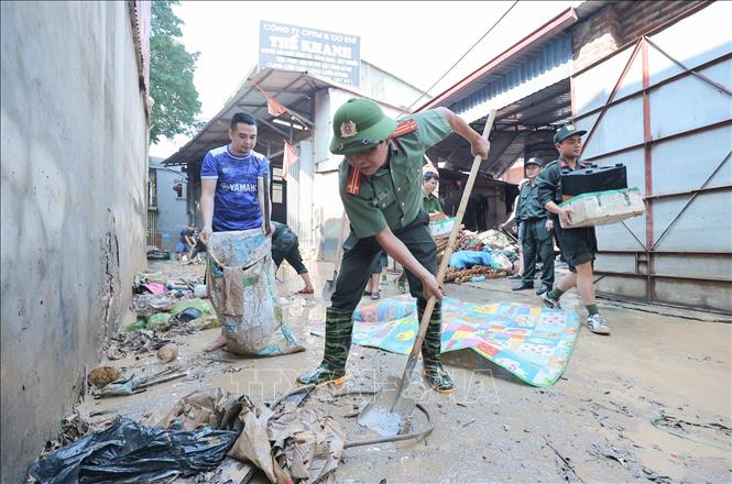 Các chiến sĩ khẩn trương thu gom rác, quét dọn bùn đất tại thôn Sông Công, xã Trung Giã, Hà Nội. Ảnh: Lê Đông - TTXVN