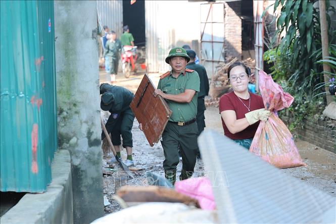 Các chiến sĩ khẩn trương thu gom rác, quét dọn bùn đất tại thôn Sông Công, xã Trung Giã, Hà Nội. Ảnh: Lê Đông - TTXVN