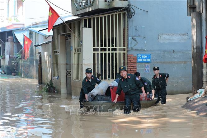 Các chiến sĩ Công an Hà Nội hỗ trợ người dân thu gom, vận chuyển tài sản hư hại do mưa lũ tại Đường Thành Công, xã Trung Giã, Hà Nội. Ảnh: Lê Đông - TTXVN