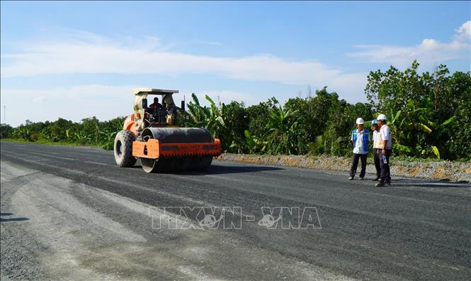 Xe lu đá mặt đường, đoạn thuộc gói thầu số 11. Ảnh: Nhựt An - TTXVN