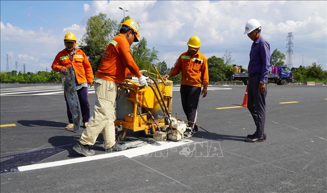 Công nhân vẽ chỉ dẫn giao thông trên mặt đường, đoạn thuộc gói thầu số 9. Ảnh: Nhựt An - TTXVN