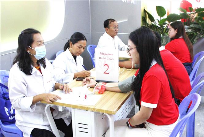 Nhân viên y tế đo huyết áp cho các tình nguyện viên là nhân viên công ty Metfone. Ảnh: Hoàng Minh- PV TTXVN tại Campuchia 