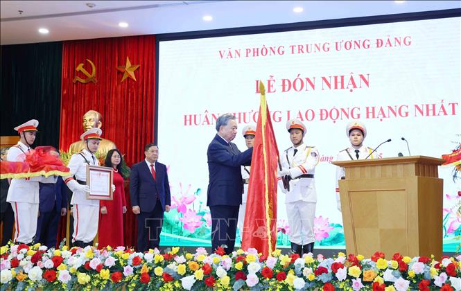 Tổng Bí thư Tô Lâm gắn Huân chương lên lá cờ truyền thống của Văn phòng Trung ương Đảng. Ảnh: Phương Hoa - TTXVN