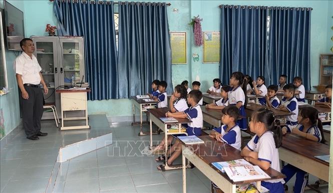 Thầy Trần Thanh Mỹ và học sinh lớp 2 Trường Tiểu học Tân Hòa A của mình. Ảnh: Đức Hạnh - TTXVN