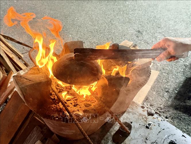 Để bánh chín vàng đều hai mặt, dùng nắp chảo nung nóng trên bếp củi rồi đậy lên chảo bánh. Ảnh: Thanh Sang - TTXVN 