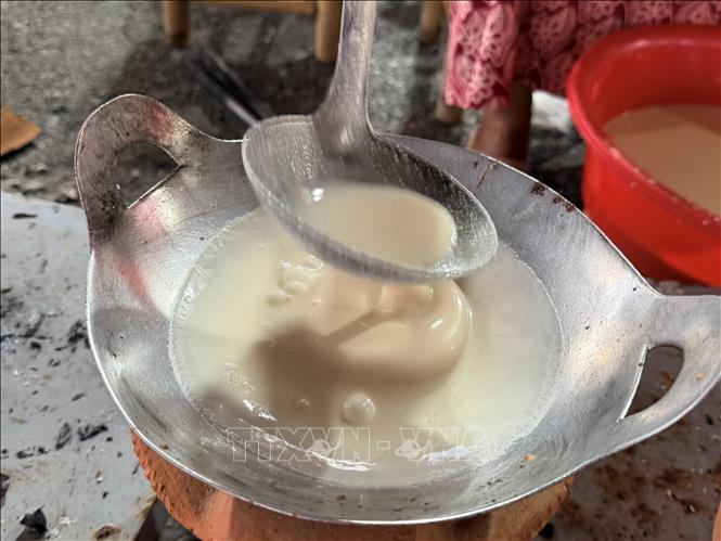 Chảo nhỏ nướng bánh trên bếp đất nung và đổ đủ lượng bột vào chảo, trong khi nướng không lật bánh lại. Ảnh: Thanh Sang - TTXVN