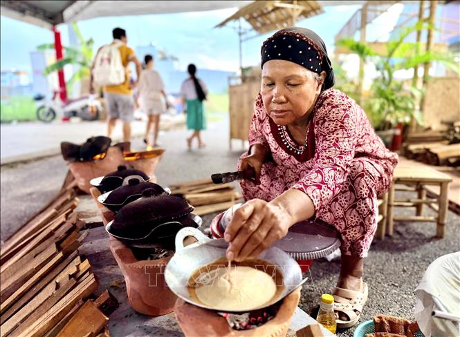 A lady checks if the cake is cooked with a bamboo stick. VNA Photo: Thanh Sang