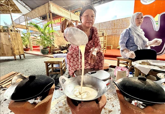 A lady pours cake batter into hot pan to make banh bo nuong. VNA Photo: Thanh Sang
