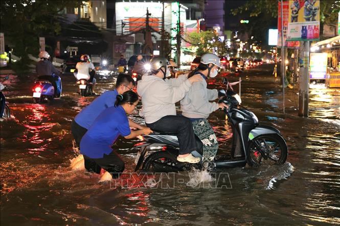 Sinh viên hỗ trợ người dân đẩy xe lên các điểm cao chờ nước rút. Ảnh: Thanh Liêm - TTXVN