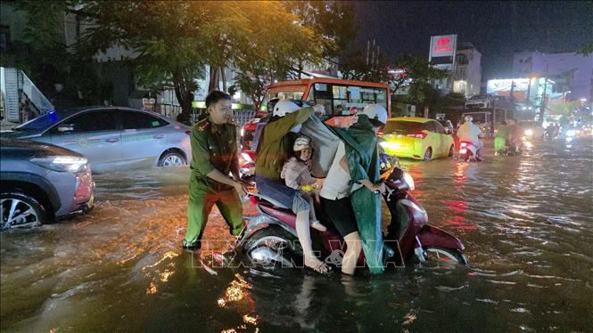 Lực lượng chức năng hỗ trợ người dân đẩy xe qua đoạn ngập sâu trên đường Cách Mạng Tháng Tám, phường Cái Khế. Ảnh: Thanh Liêm - TTXVN