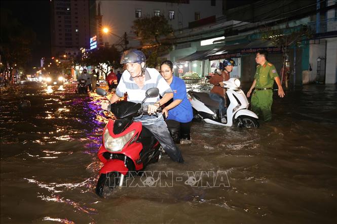 Sinh viên hỗ trợ người dân đẩy xe lên các điểm cao chờ nước rút. Ảnh: Thanh Liêm - TTXVN