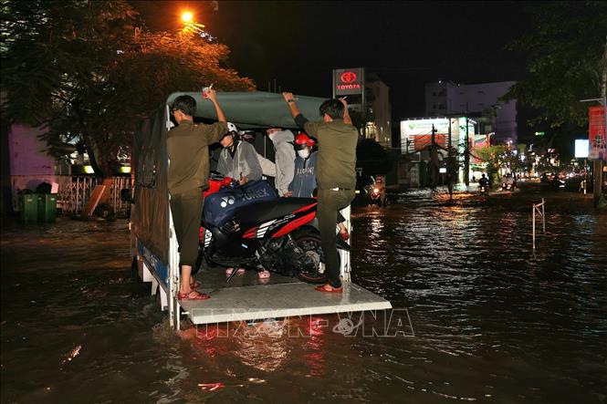 Lực lượng chức năng đem xe tải ra vận chuyển xe máy giúp người dân qua điểm ngập sâu trên đường Cách Mạng Tháng Tám. Ảnh: Thanh Liêm - TTXVN