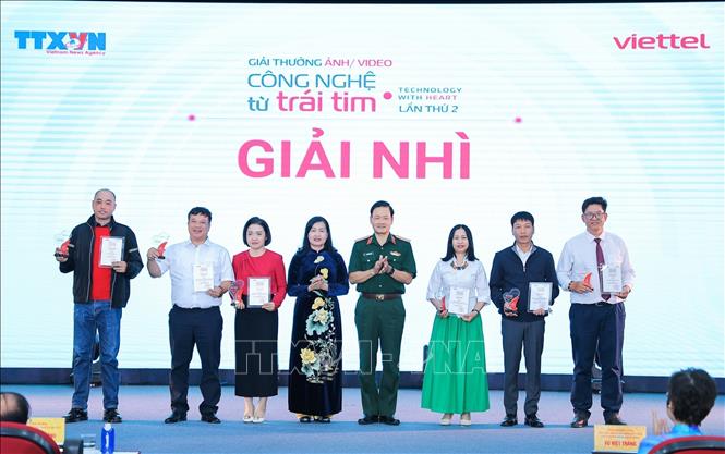 Bà Trần Thị Thu Đông, Phó Chủ tịch Liên hiệp các Hội Văn học Nghệ thuật Việt Nam, Chủ tịch Hội Nghệ sĩ Nhiếp ảnh Việt Nam và Trung tướng Nguyễn Văn Đức, Cục trưởng Cục Tuyên huấn, Bộ Quốc phòng trao giải Nhì cho các tác giả. Ảnh: Lê Đông - TTXVN