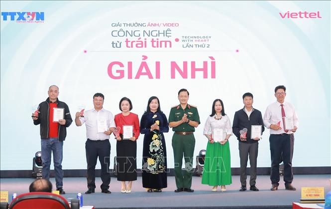 Bà Trần Thị Thu Đông, Phó Chủ tịch Liên hiệp các Hội Văn học Nghệ thuật Việt Nam, Chủ tịch Hội Nghệ sĩ Nhiếp ảnh Việt Nam và Trung tướng Nguyễn Văn Đức, Cục trưởng Cục Tuyên huấn, Bộ Quốc phòng trao giải Nhì cho các tác giả. Ảnh: Phan Phương - TTXVN