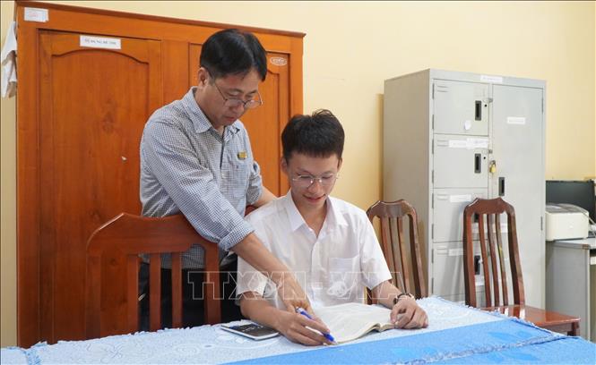 Thầy Sơn hướng dẫn học sinh làm bài. Ảnh: Nhựt An - TTXVN