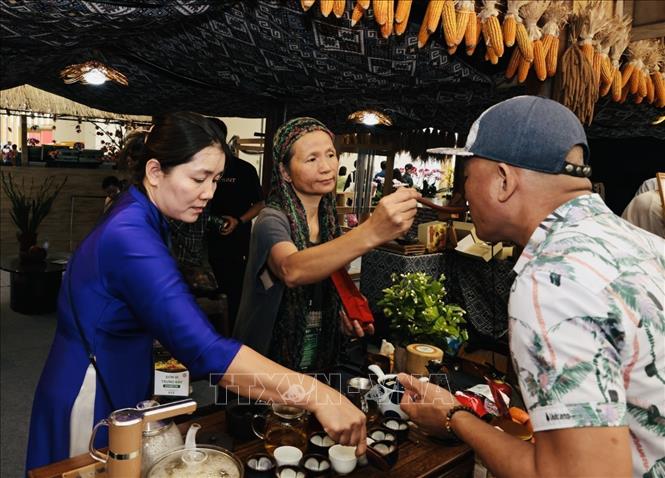 Mời du khách thưởng thức hương trà của gian hàng đến từ Sơn La. Ảnh: Trần Việt - TTXVN