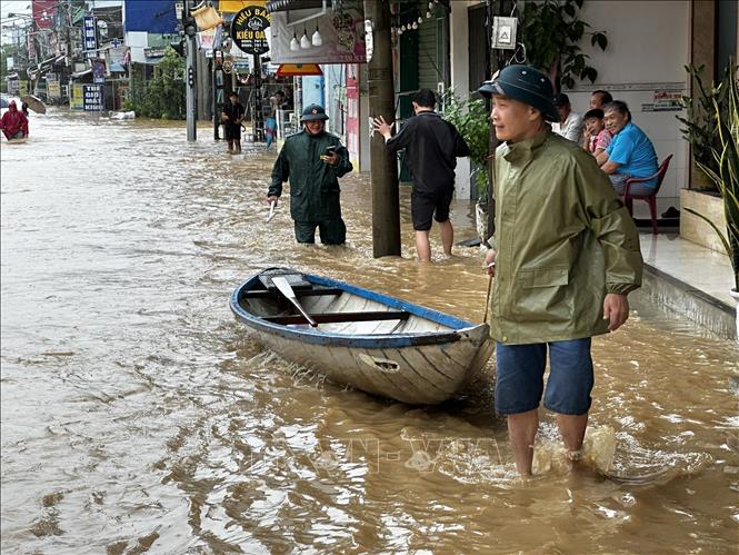  Lực lượng chức năng đưa các phương tiện ghe thuyền vào để hỗ trợ người dân vùng ngập xã Đại Lộc. Ảnh: Trần Lê Lâm - TTXVN