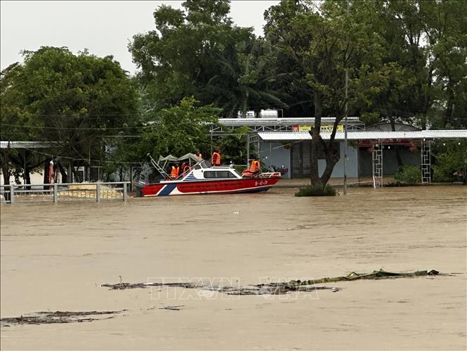 Lực lượng chức năng dùng thuyền máy di chuyển vào vùng ngập sâu giúp dân tại xã Đại Lộc. Ảnh: Trần Lê Lâm - TTXVN